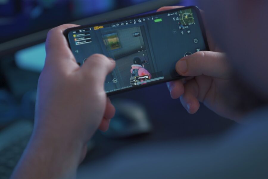 Mobile gamer hand holding smartphone anime gacha screen